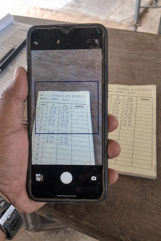 Telefon merakam kad kehadiran tulis tangan di meja tapak.